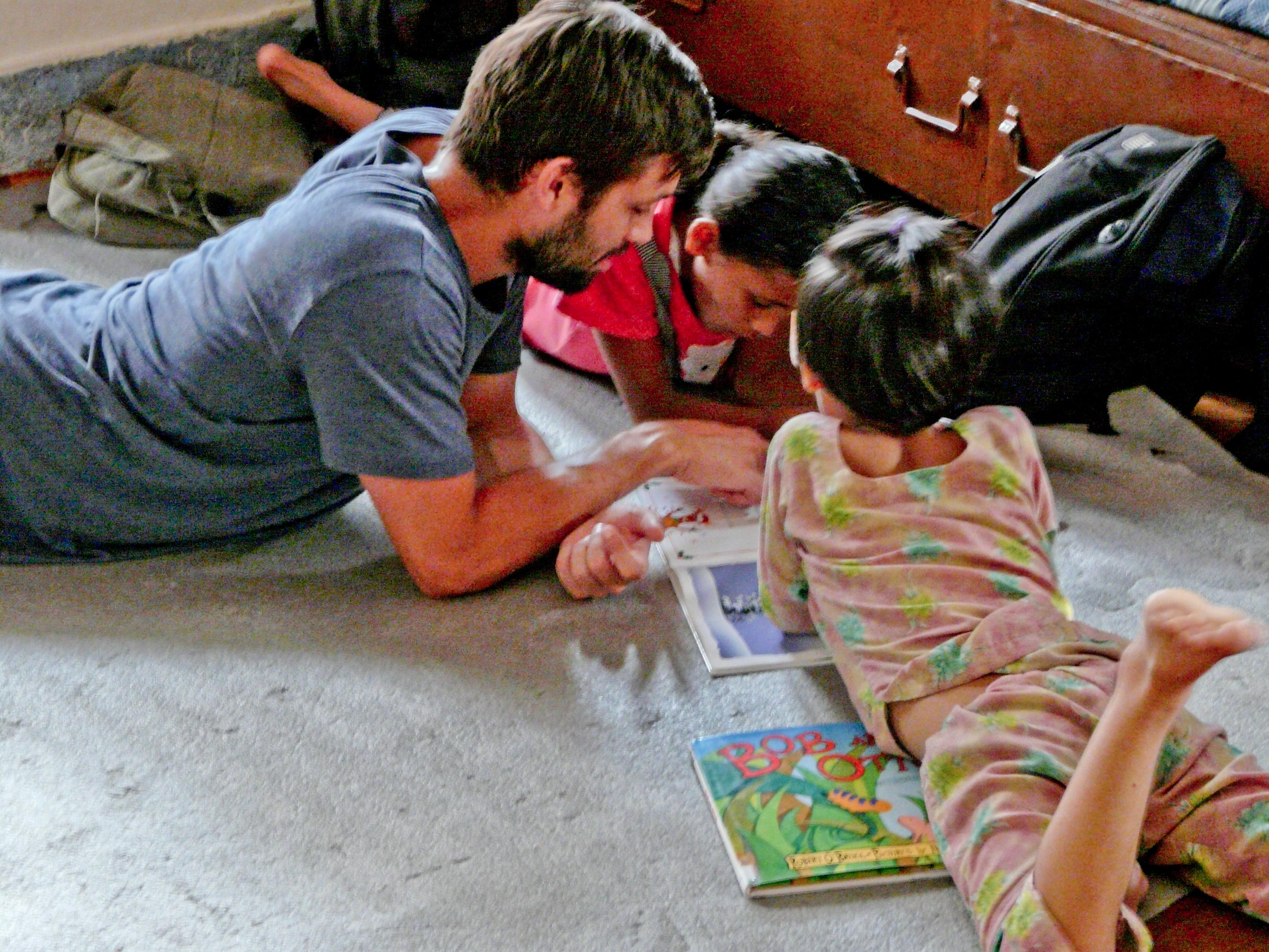A Teaching volunteer reads a book to children at his volunteer teaching placement in Nepal A Projects Abroad volunteer teaching English in Nepal reads a book to his students